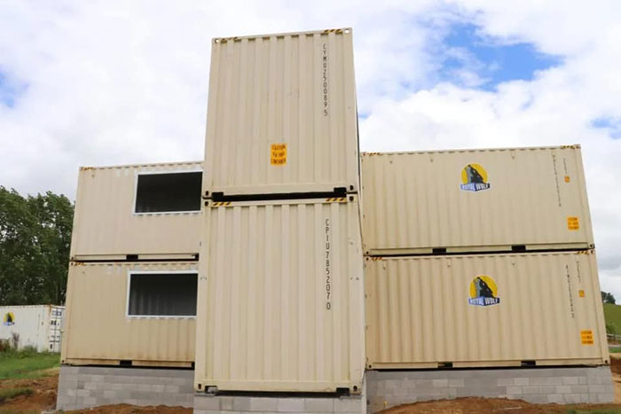 House built with shipping containers, featuring an impressive modular design under a clear blue sky.