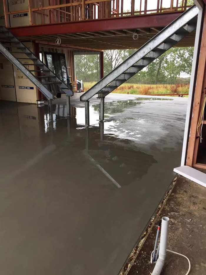Interior construction of a house built from shipping containers with metal stairs and unfinished walls.
