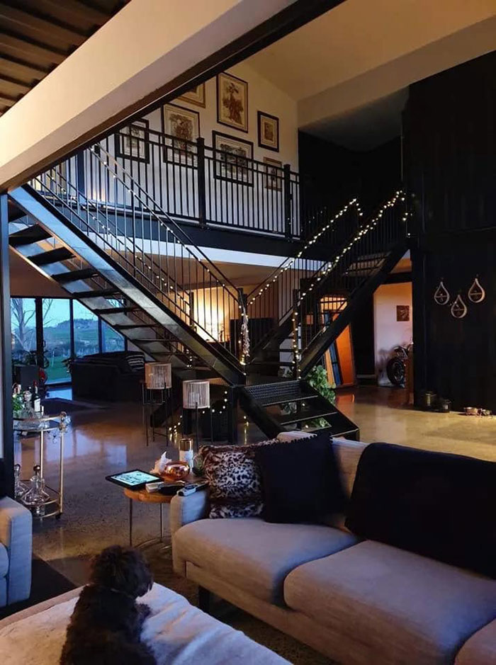 Interior of a house built from shipping containers, featuring modern decor and a sleek staircase.