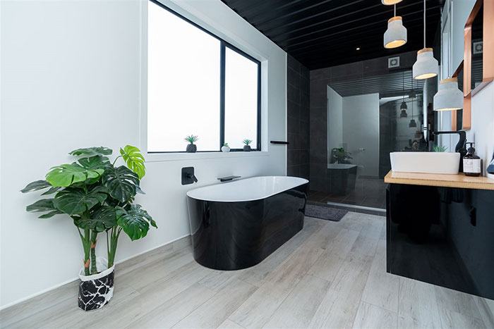 Modern bathroom interior with sleek black tub, wooden vanity, and hanging lights in a stunning shipping container house.