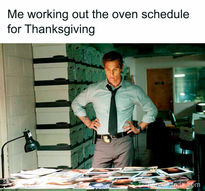 Man planning Thanksgiving oven schedule with intense focus, surrounded by photos and files in an office setting.