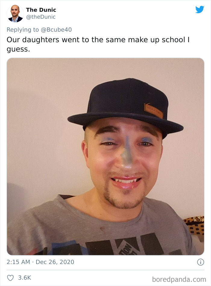 Man wearing a black cap with colorful makeup on his face after a visit to daughters' beauty salons, smiling awkwardly.