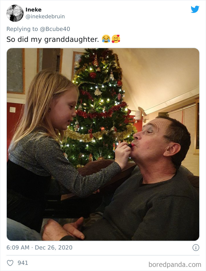 A dad getting makeup applied by his daughter in front of a decorated Christmas tree after a visit to beauty salons.