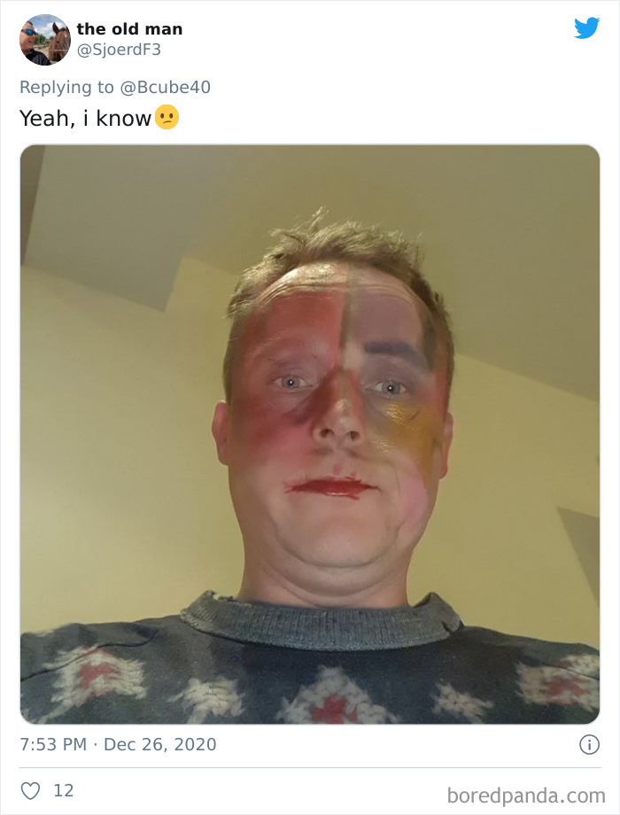 Man with uneven colorful face paint after a visit to his daughter's beauty salon, wearing a patterned sweater.