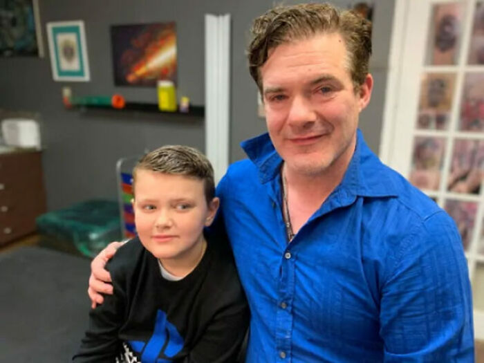 Father with tattoo matching his son's birthmark, both smiling in a room together. Father with tattoo matching his son's birthmark, both smiling in a room together.