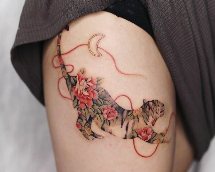 Tiger tattoo with floral design on arm, showcasing beautiful body art by a skilled tattoo artist.