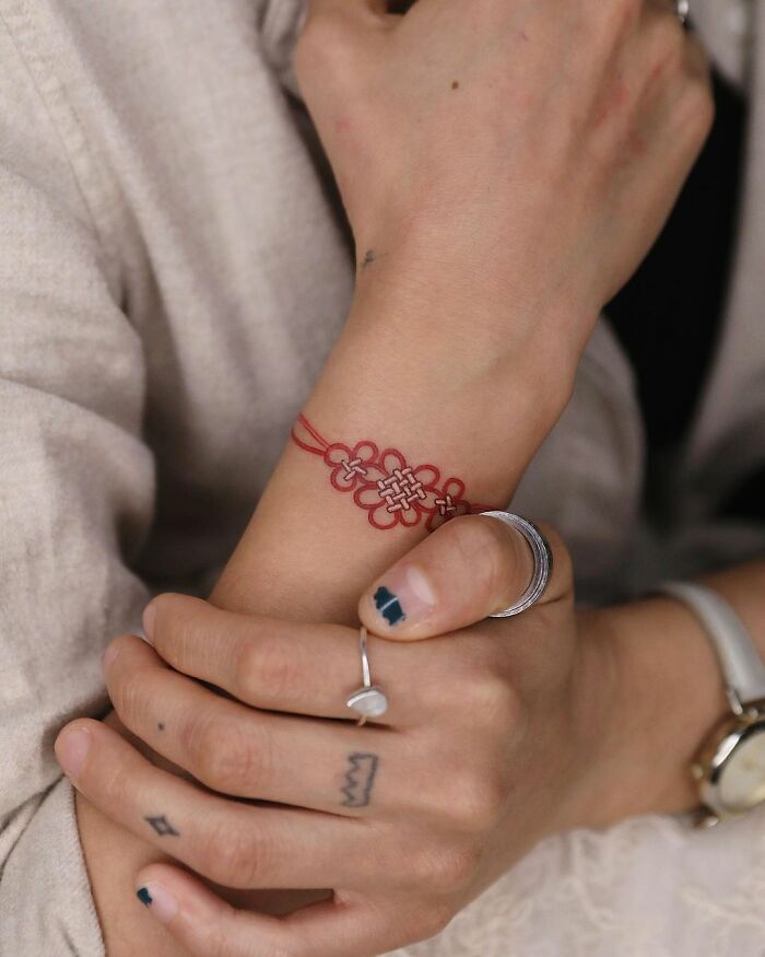 Intricate red wrist tattoo by tattoo artist Sion Kwak, showcasing beautiful body art details.