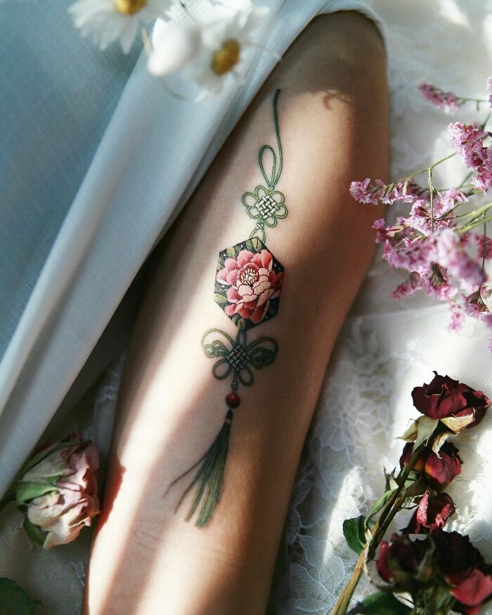 Beautiful body art featuring a floral tattoo design on skin, surrounded by delicate flowers and lace.