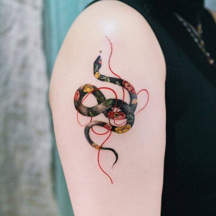 Beautiful body art featuring a floral-patterned snake tattoo on an arm.