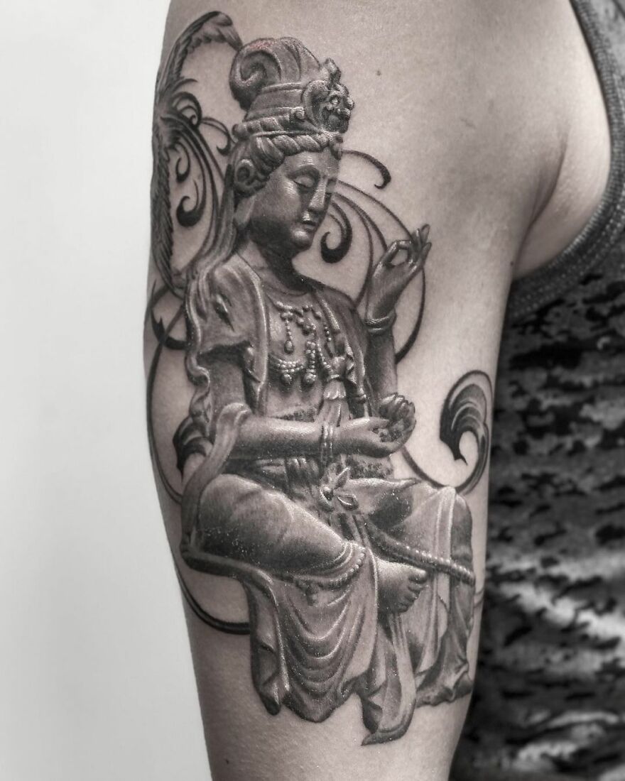 Black and gray realism tattoo of a seated figure with intricate details on a person's arm.
