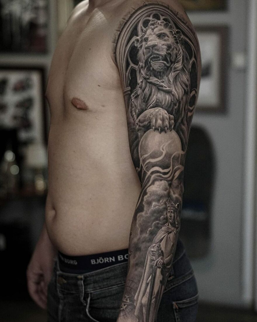 Tattoo of a lion and a robed figure on a man's arm, showcasing black and gray realism by a Swedish artist.
