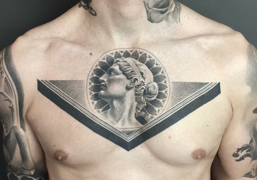 Chest tattoo of a classical sculpture design, showcasing black and gray realism by a Swedish artist.