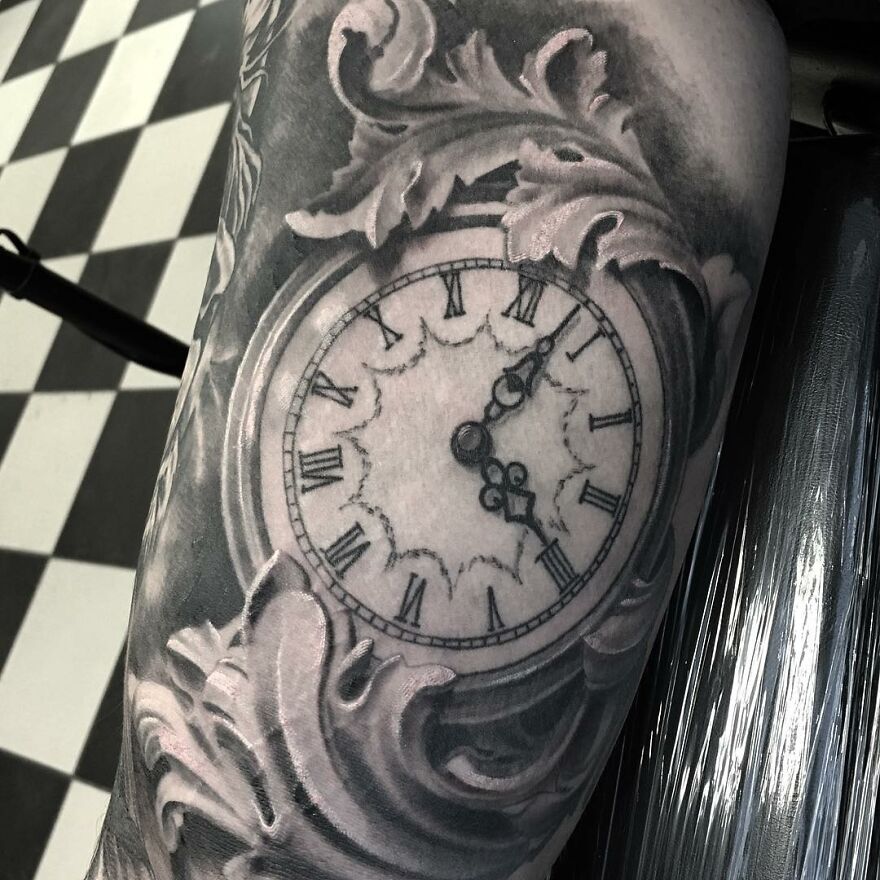 Black and gray realism tattoo of a decorative clock with Roman numerals on a person's arm.