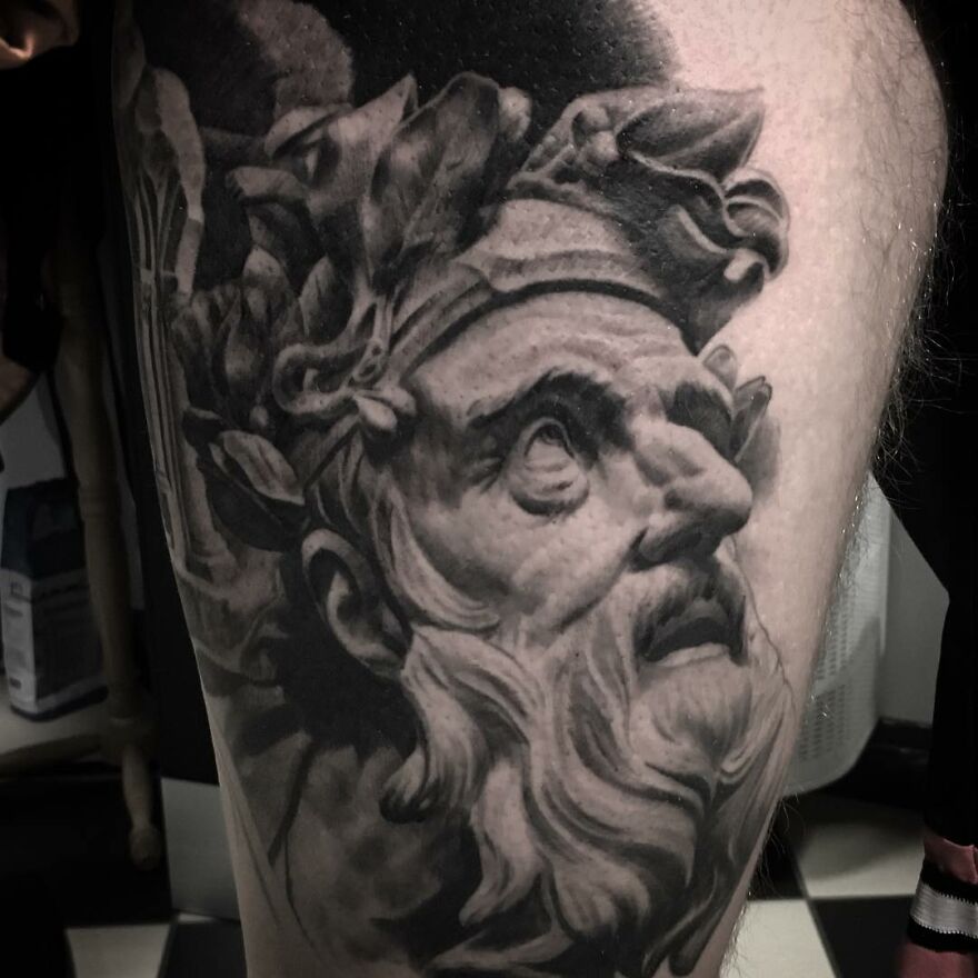 Black and gray realism tattoo by Swedish artist, depicting a classical bearded figure with laurel wreath.