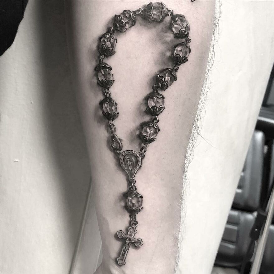 Black and gray realism tattoo of a rosary on a person's forearm by a Swedish artist.