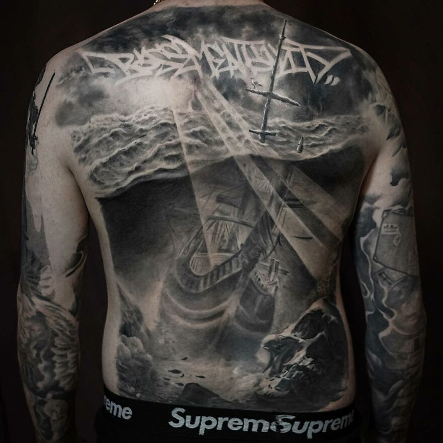 Back tattoo in black and gray realism by Swedish artist, depicting a ship scene under stormy skies.