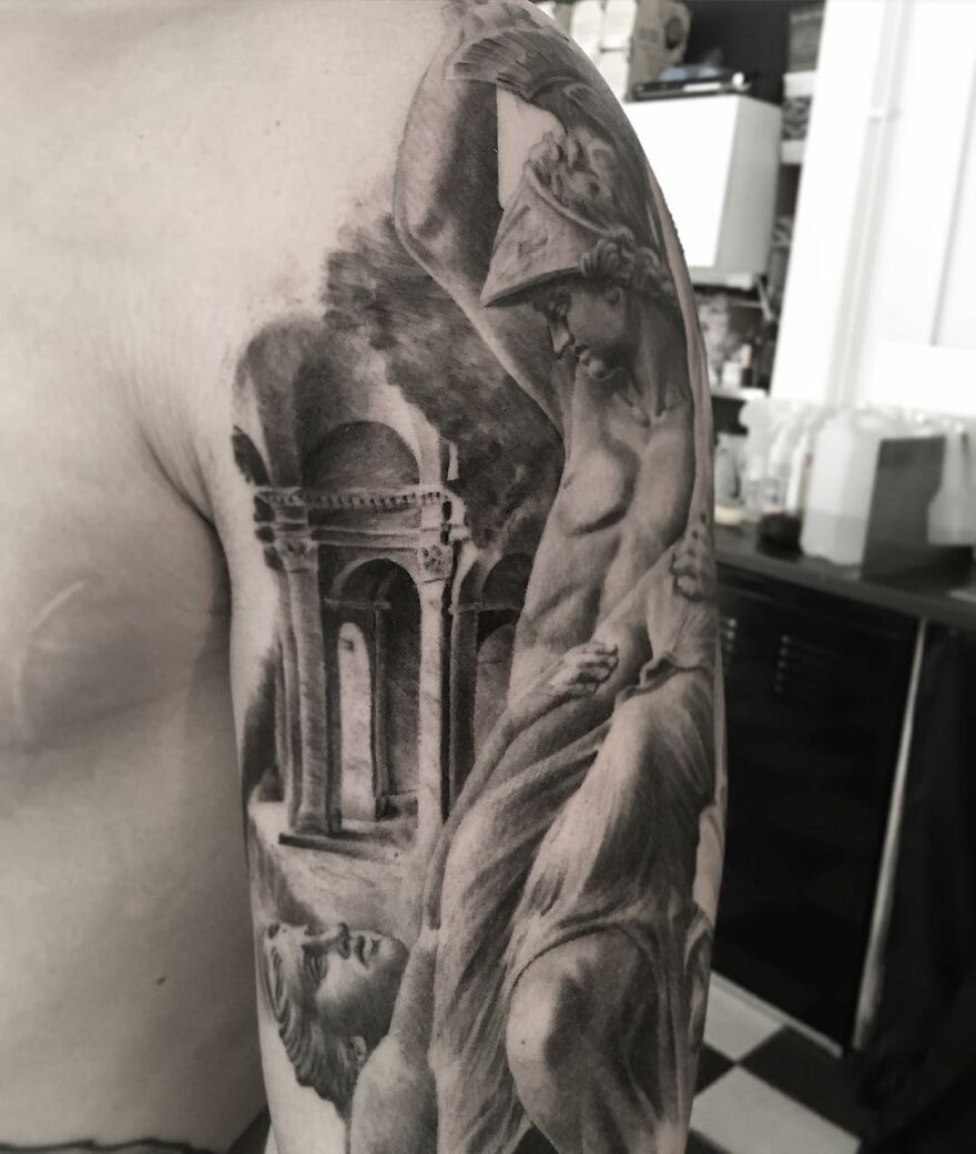 Black and gray realism tattoo on arm depicting classical statues and architectural elements.