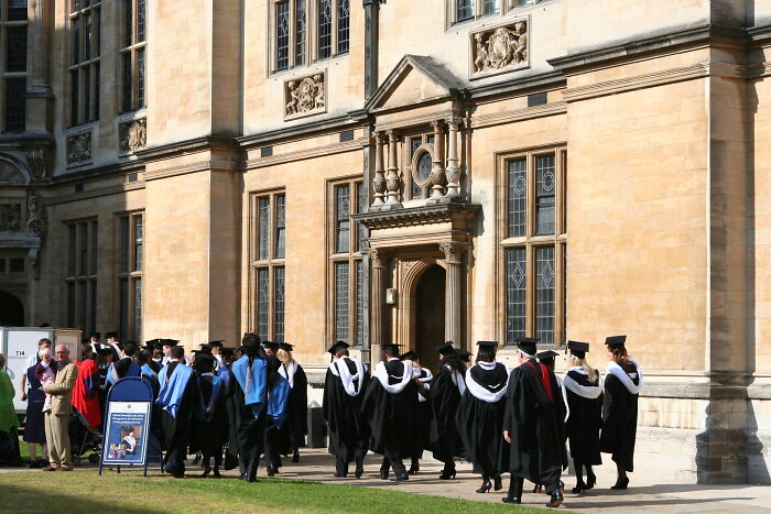 Graduates in caps and gowns walking outside a historic university building, representing education and interesting facts not learned at school.