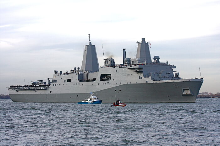 Large modern naval ship sailing on the ocean with two small boats nearby, illustrating interesting facts not learned at school.
