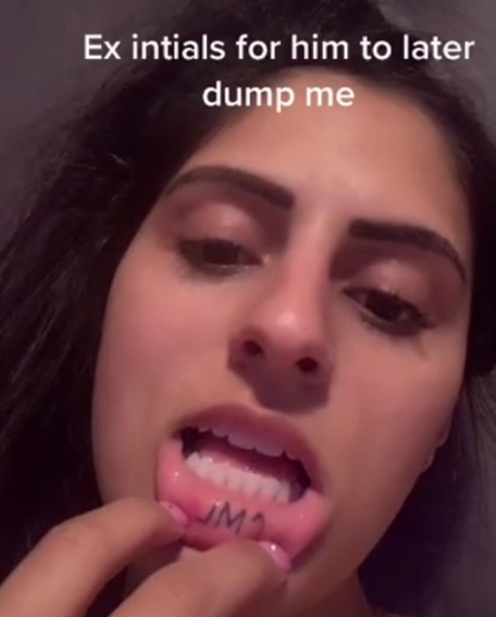 Woman shows "JM" tattoo inside lip, sharing her dumbest tattoo experience.