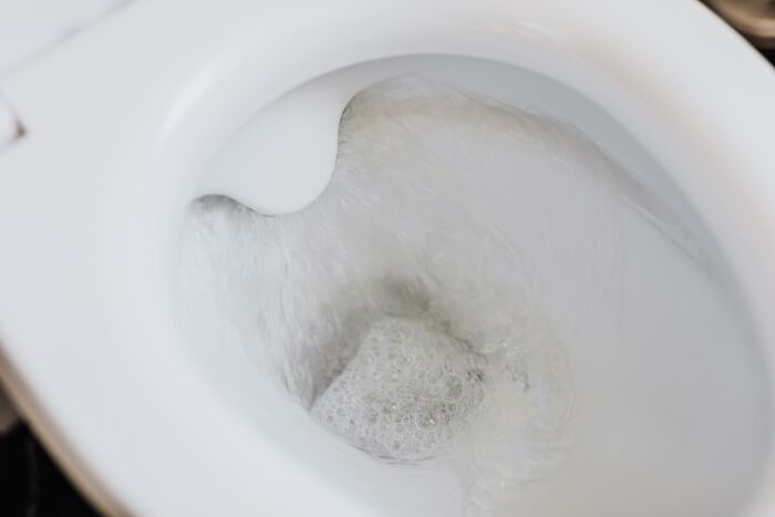Toilet flushing with clear water swirling inside the bowl, illustrating a fact people didn’t learn at school.