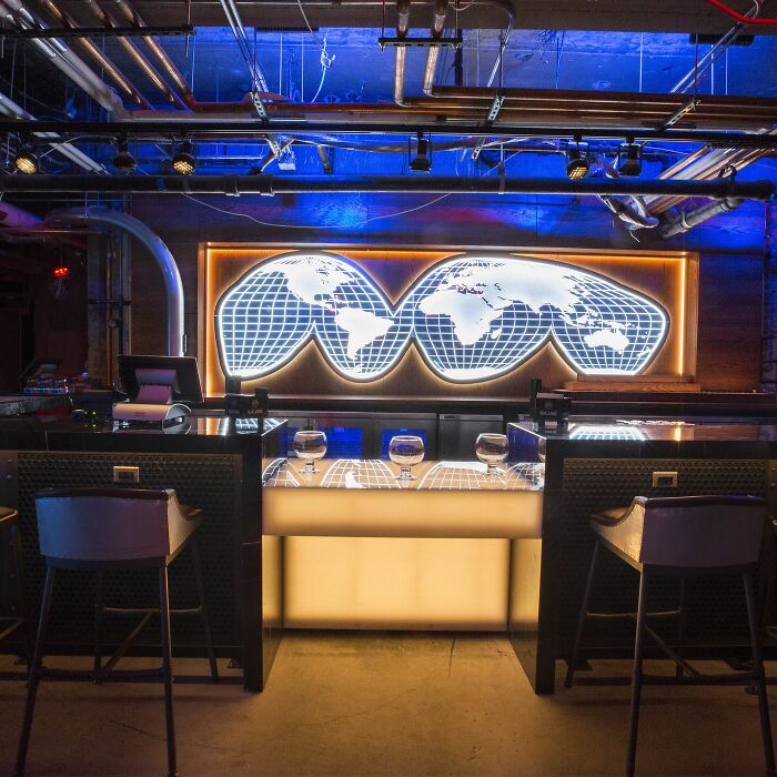 Modern bar interior with illuminated world map artwork and stylish seating, highlighting interesting facts people didn't learn at school.