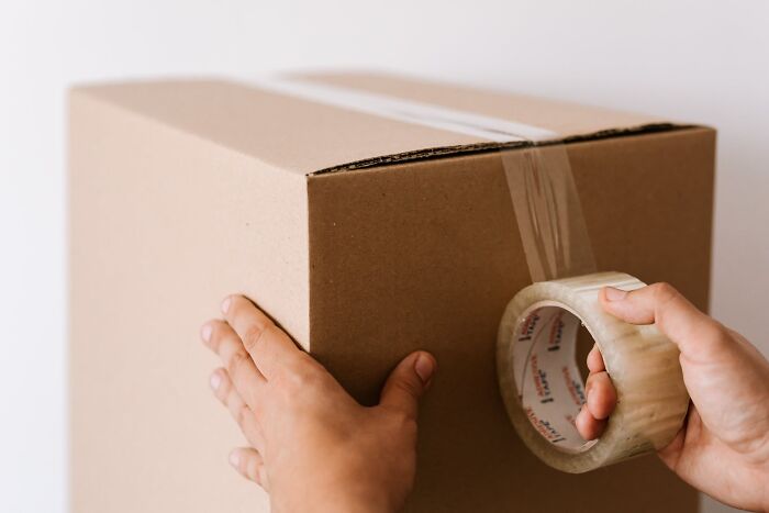 Hands sealing a cardboard box with packing tape, illustrating the concept of interesting facts people didn't learn at school.