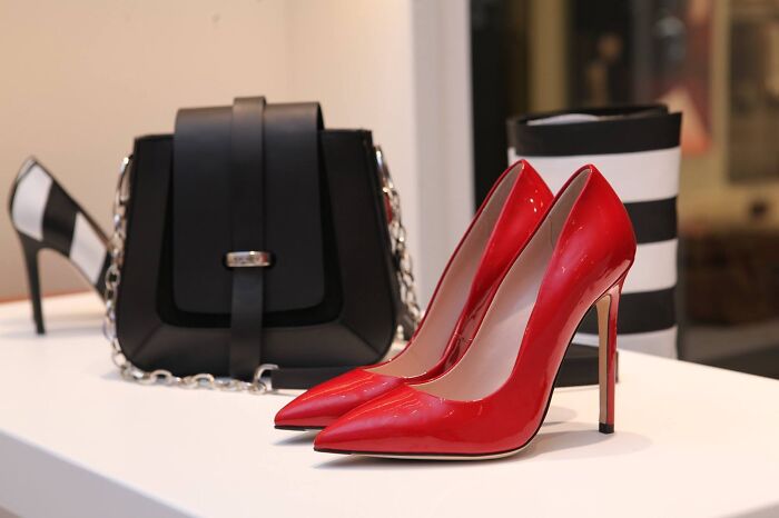 Red high heels and black handbag displayed on a white surface showcasing fashion accessories for today I learned facts.