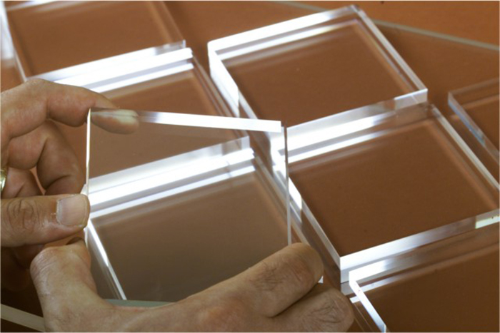 Hands holding a clear glass square among several glass pieces, illustrating interesting facts people didn’t learn at school.