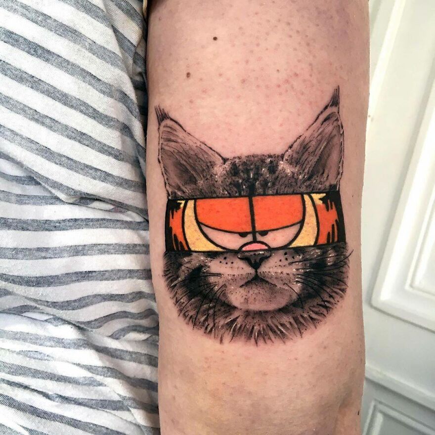 Tattoo of a cat with a whimsical eyepatch, combining two distinct artistic styles on an arm.