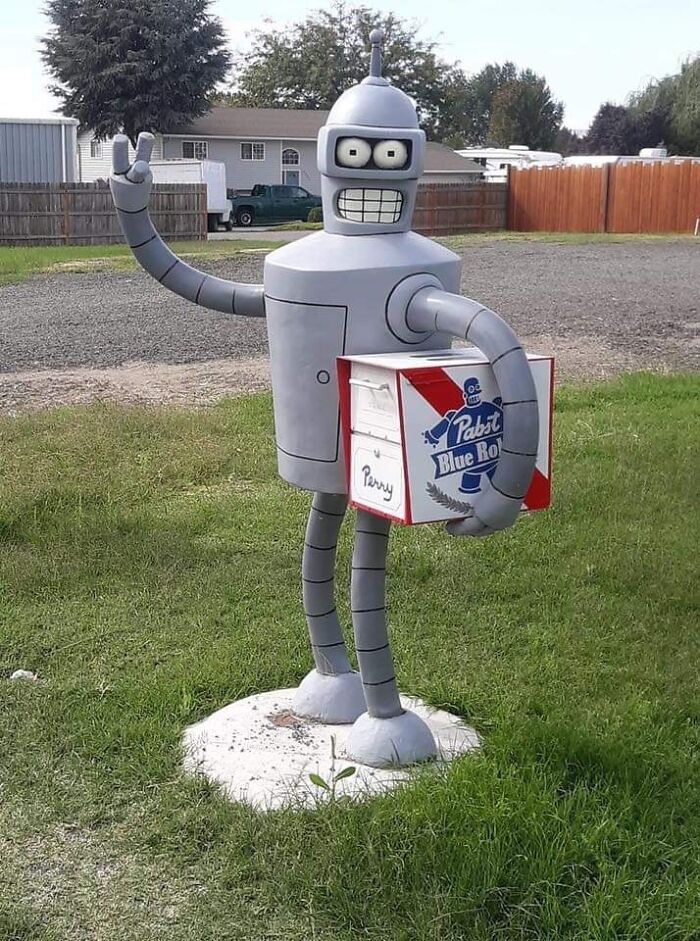 Robot holding a creative and cool mailbox designed like a Pabst Blue Ribbon beer box outdoors on grass. Robot holding a creative and cool mailbox designed like a Pabst Blue Ribbon beer box outdoors on grass.