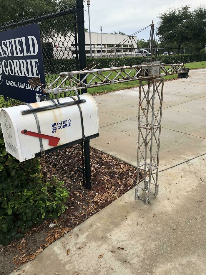 Creative and cool mailbox designed like a construction crane, featuring a white mailbox with red flag on a sidewalk.