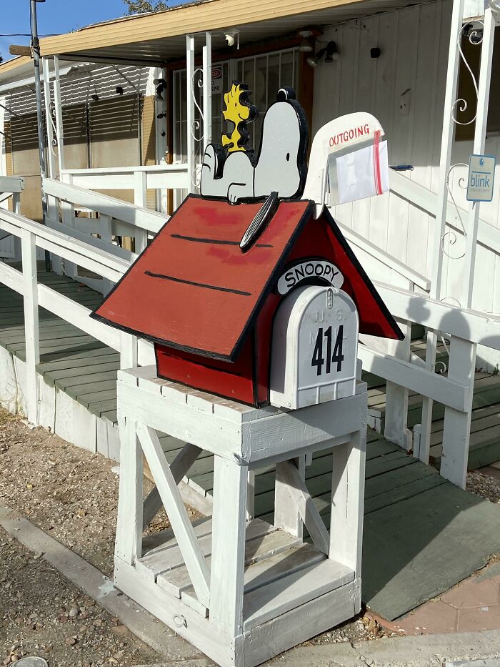 Creative and cool mailbox designed like Snoopy's doghouse with mailbox number 414 and outgoing mail flag displayed outdoors.