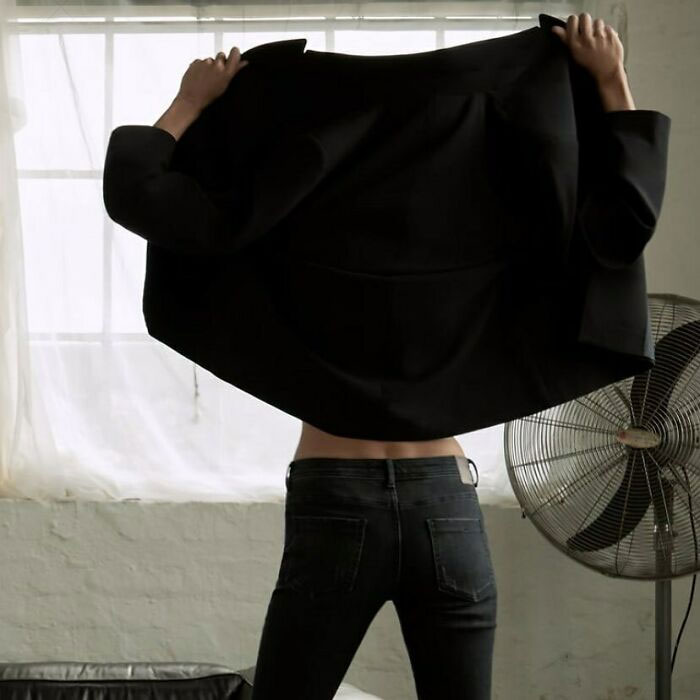 Model in unusual pose holding black jacket, highlighting Zara's unique online shopping challenges.