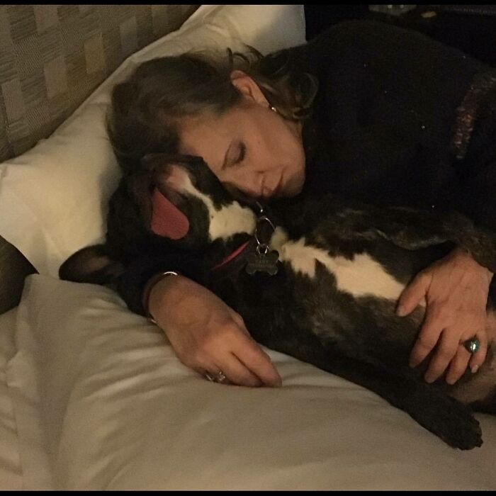 Celebrity cuddling with their dog on a bed, showing immense love and affection for dogs in a cozy setting.