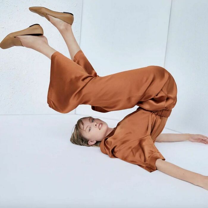 Model in unusual pose wearing brown outfit, highlighting Zara's unique online shopping challenges.