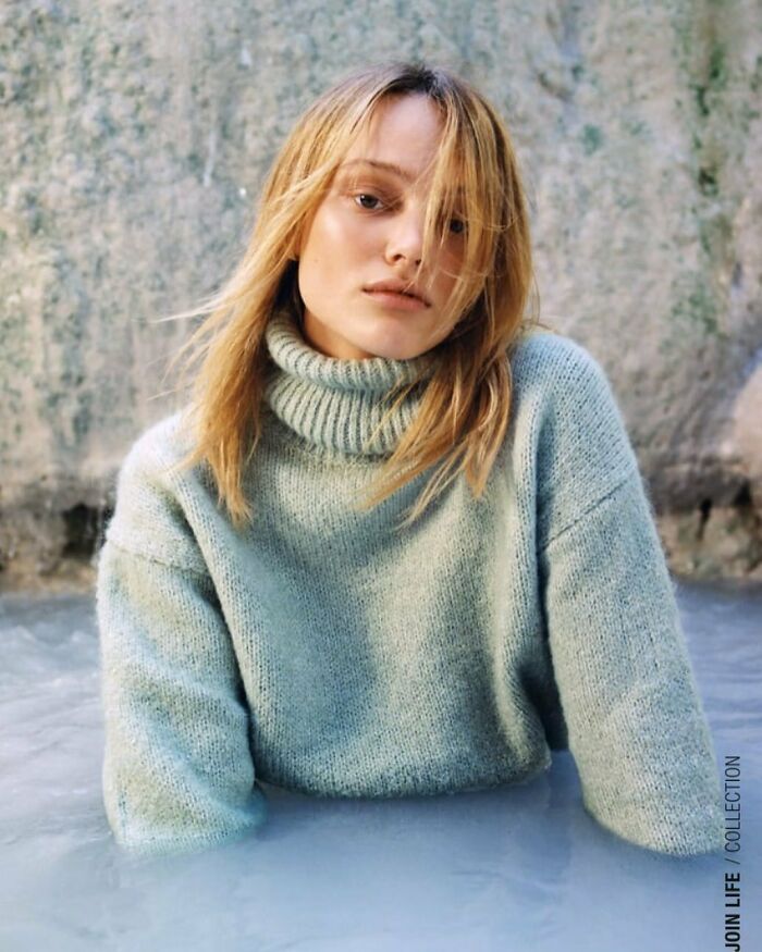 Model in a turtleneck sweater sitting in water, showcasing Zara's unique modeling poses.
