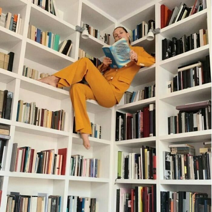 Zara shopper poses unusually on bookshelf, highlighting bizarre modeling styles.