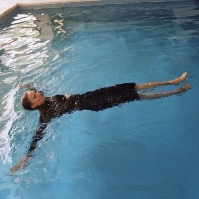 Model floating in a pool wearing a black outfit, highlighting Zara’s unconventional modeling poses.