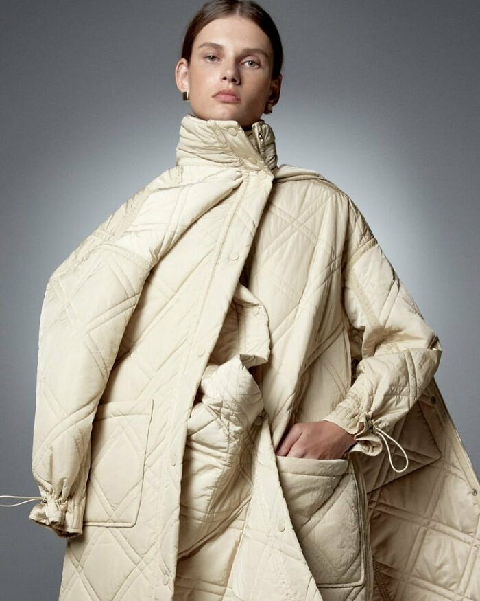 Model wearing a cream quilted coat in an unusual pose for Zara's online shopping platform.