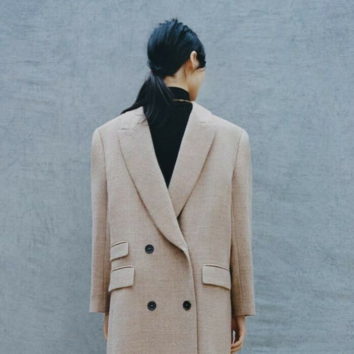 Zara model in a tan blazer faces away, highlighting online shopping challenges with unusual poses.