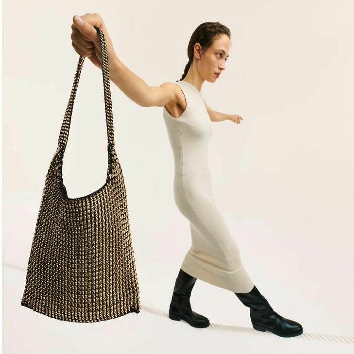 Model striking a unique pose with a woven bag, highlighting Zara's unusual styling in online shopping images.