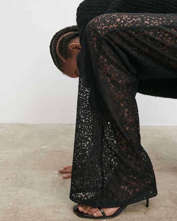 Model in unusual pose wearing black lace pants, highlighting Zara's unique fashion photography style.