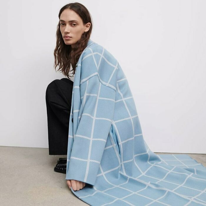 Model posing in a blue checkered coat, highlighting Zara's unconventional modeling poses.