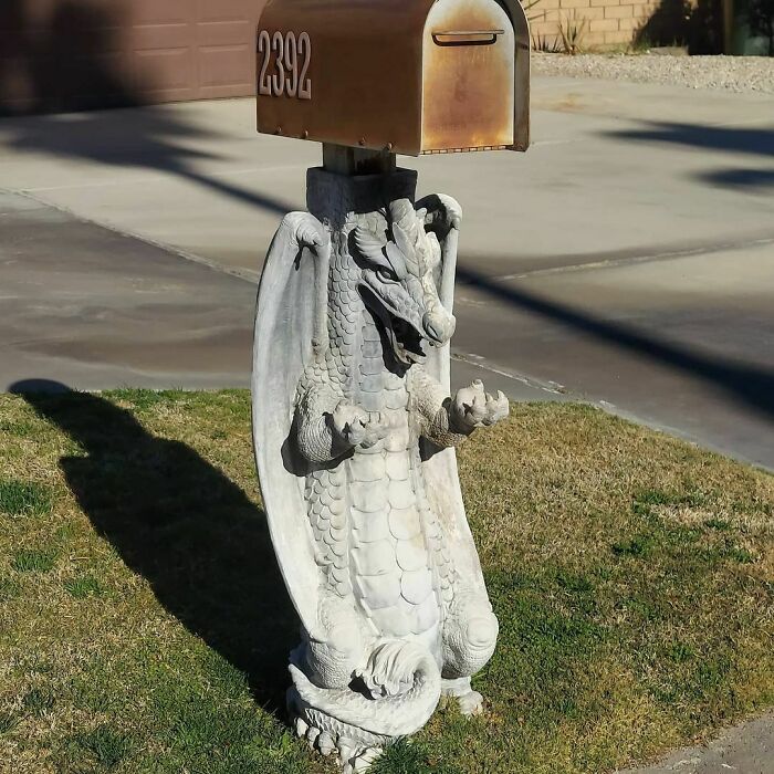 Creative mailbox design featuring a dragon statue base supporting a numbered mailbox on a residential lawn.