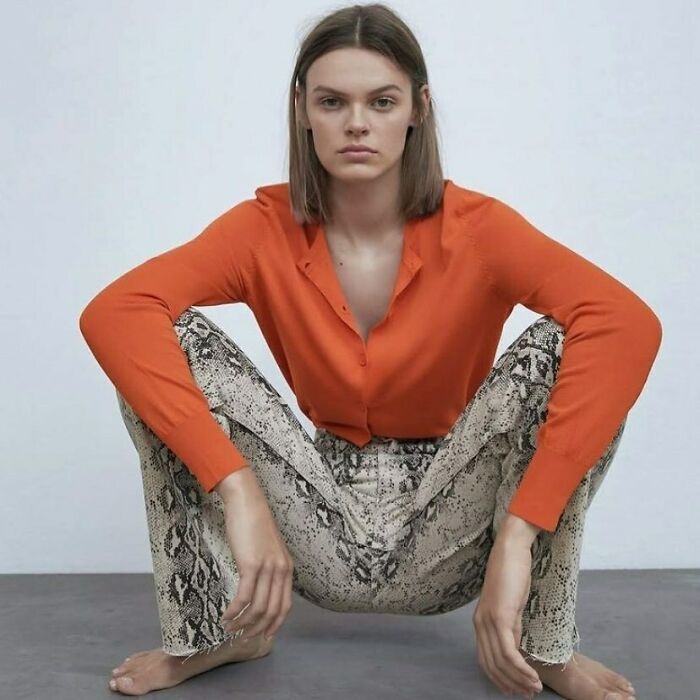 Model in unusual pose wearing an orange top and snake-print pants, highlighting Zara's odd modeling choices.