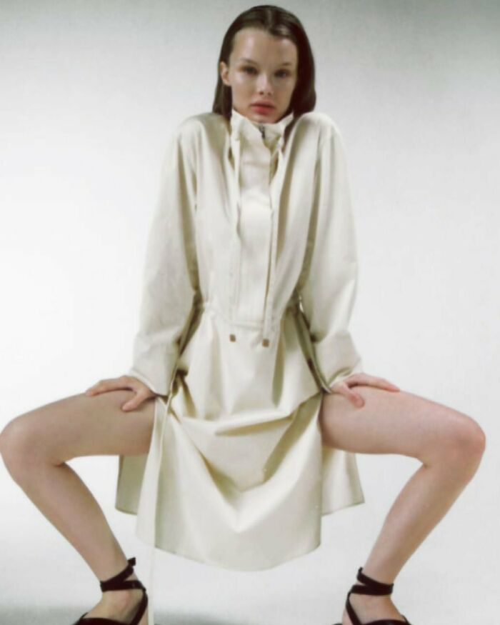 Model in an unusual pose wearing a white Zara dress, highlighting issues with online shopping due to modeling choices.