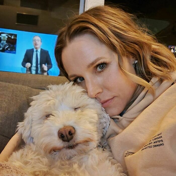 Actress cuddling her fluffy white dog indoors, showing genuine love and affection for dogs.
