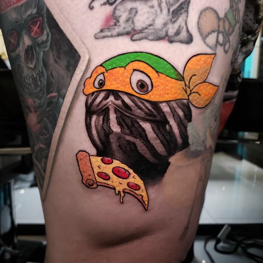 Tattoo combining cartoon style turtle with pizza, showcasing two different tattoo styles on skin.