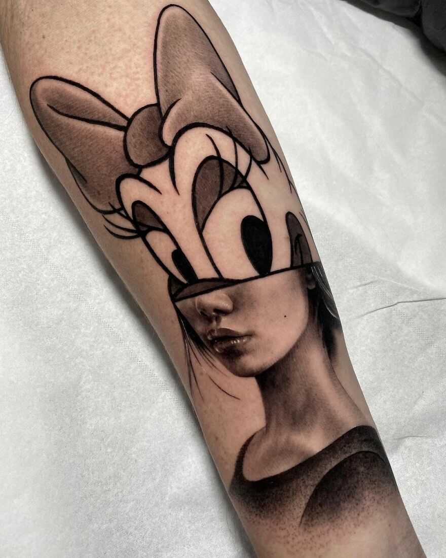 Tattoo on arm combining two styles: a cartoon character and a realistic portrait by Mat Rule.